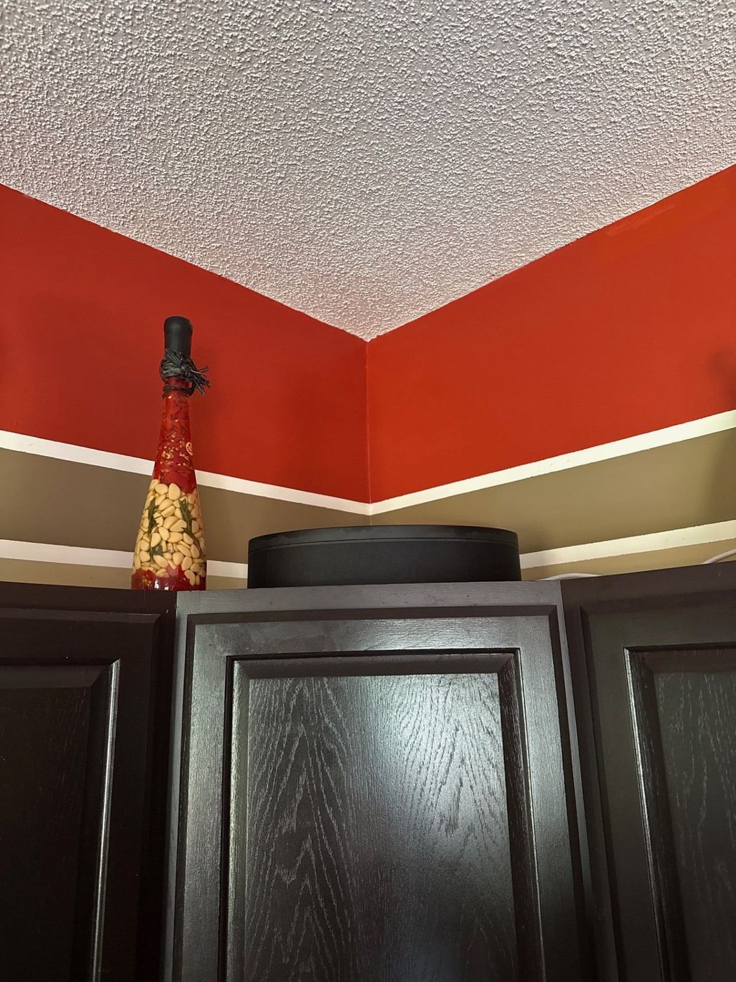 Wireless speaker for a kitchen music zone placed discreetly above dark wood cabinets