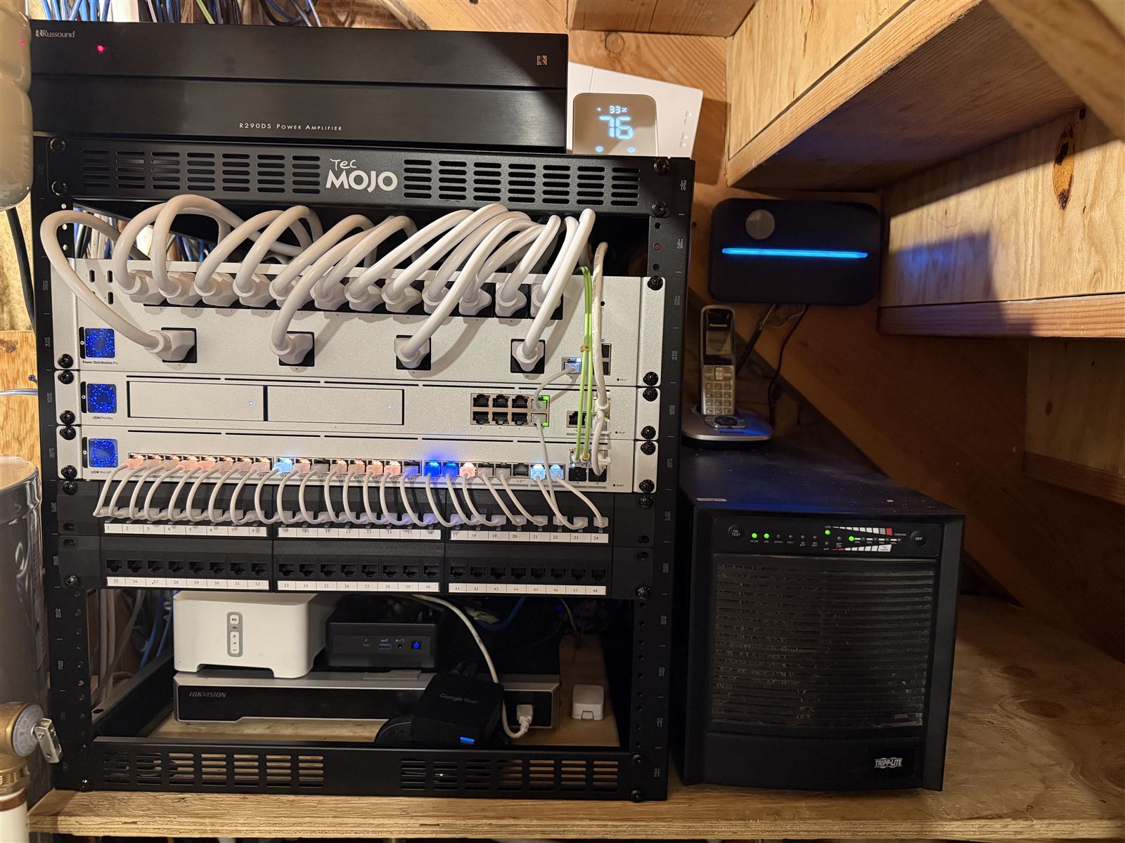 Professionally rebuilt network rack with labeled patch panels, neatly looped cables, UniFi network gear, and battery backup