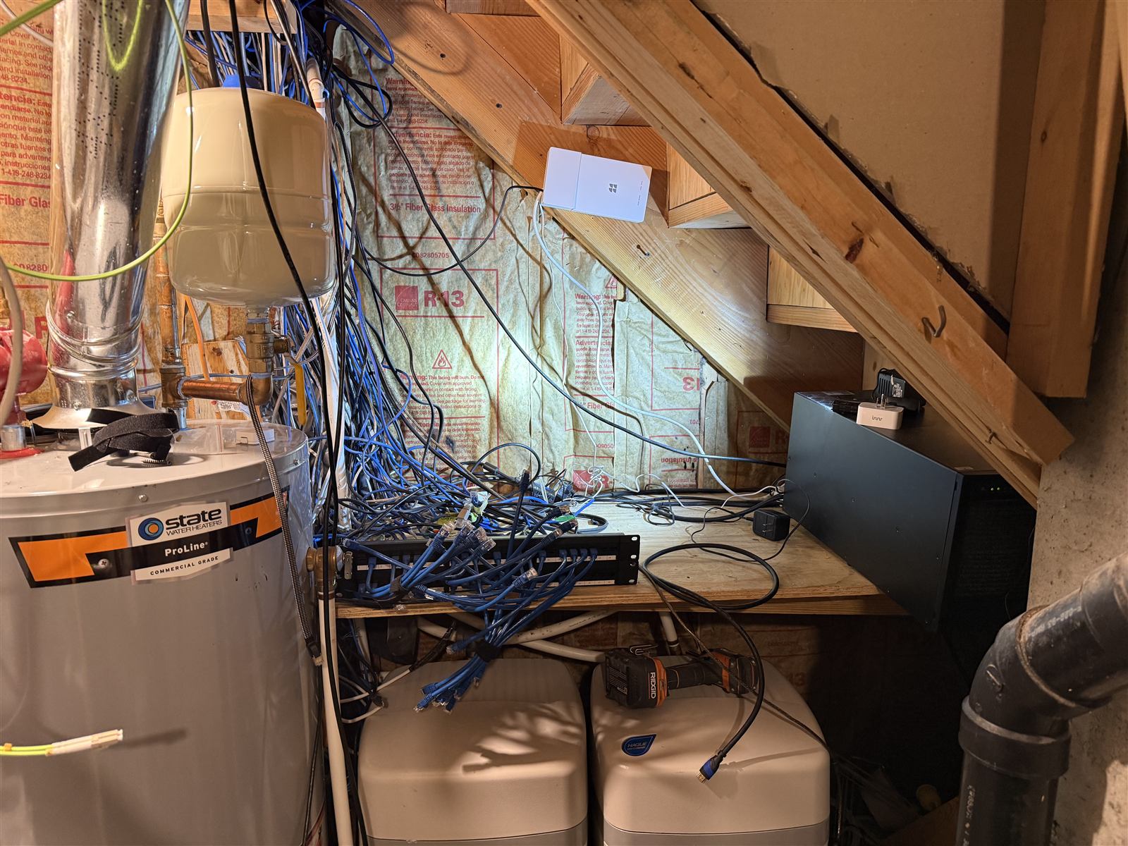 Before: a patch panel dangling in a utility room with a tangle of unlabeled blue cables beside the water heater