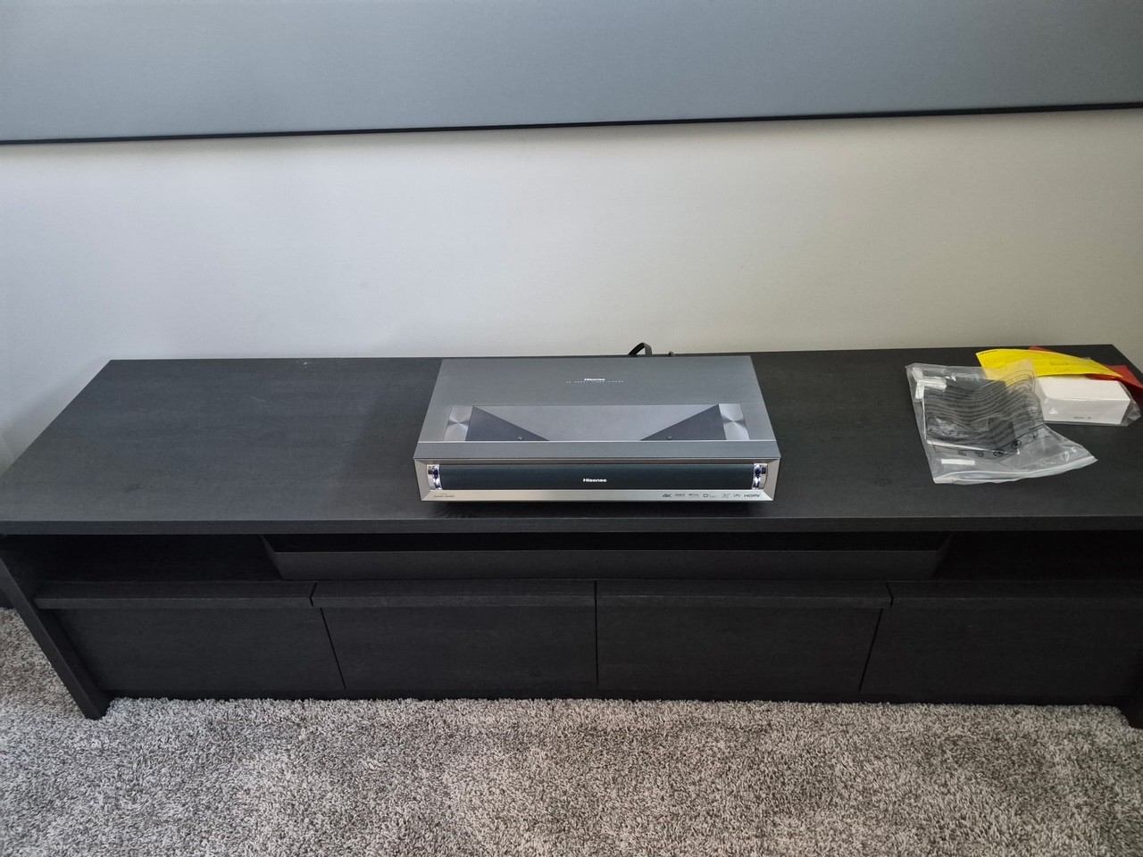 Ultra-short-throw laser projector on a low console beneath a large fixed-frame screen